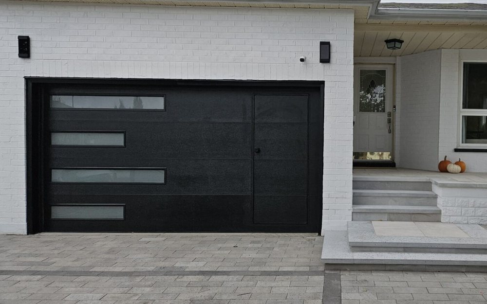 Black modern walk-through garage door with a built-in side entry door and horizontal glass panels